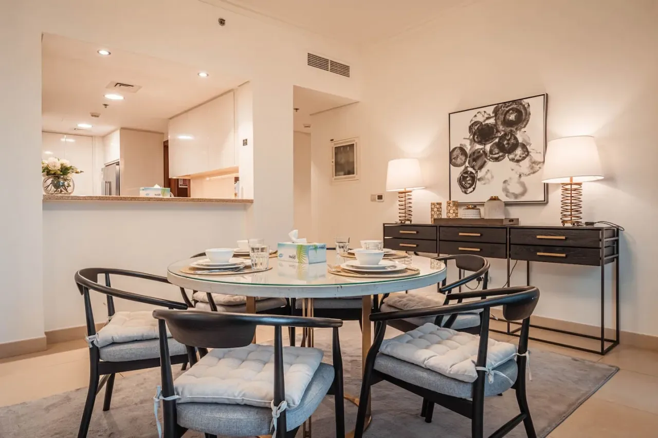 Un comedor con una mesa redonda, asientos acolchados y un aparador.