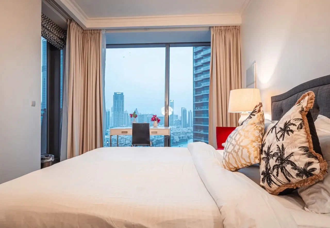 Un dormitorio con una cama grande y vistas de la ciudad por la ventana.