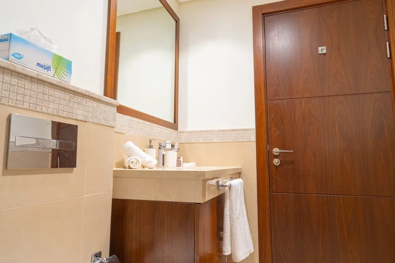 Un lavabo de baño con espejo y toalla junto a una puerta de madera.