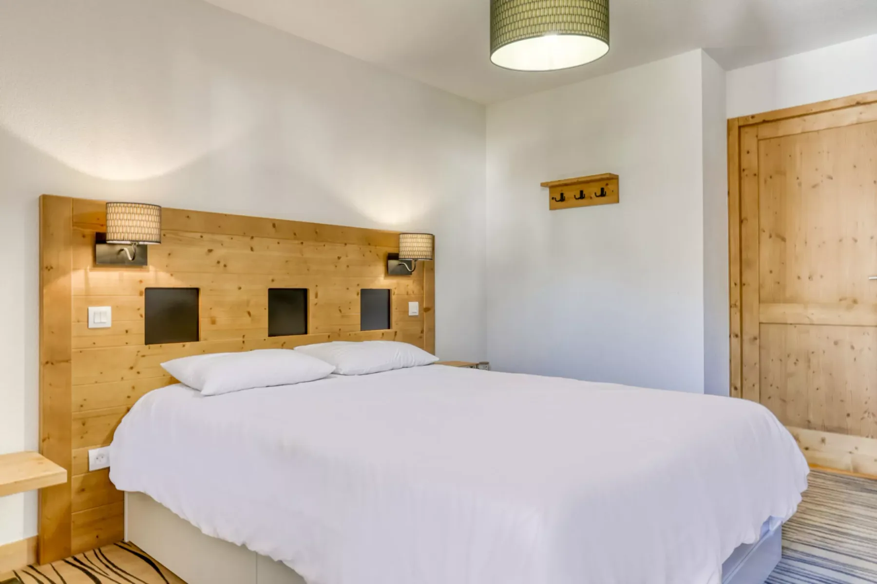 Un dormitorio con una cama grande junto a un cabecero de madera.