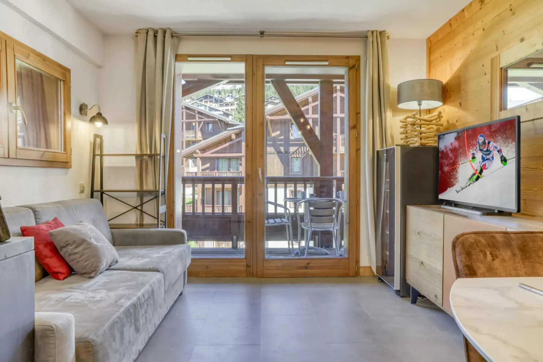 Living room with seating, a television, and glass doors opening onto a balcony.