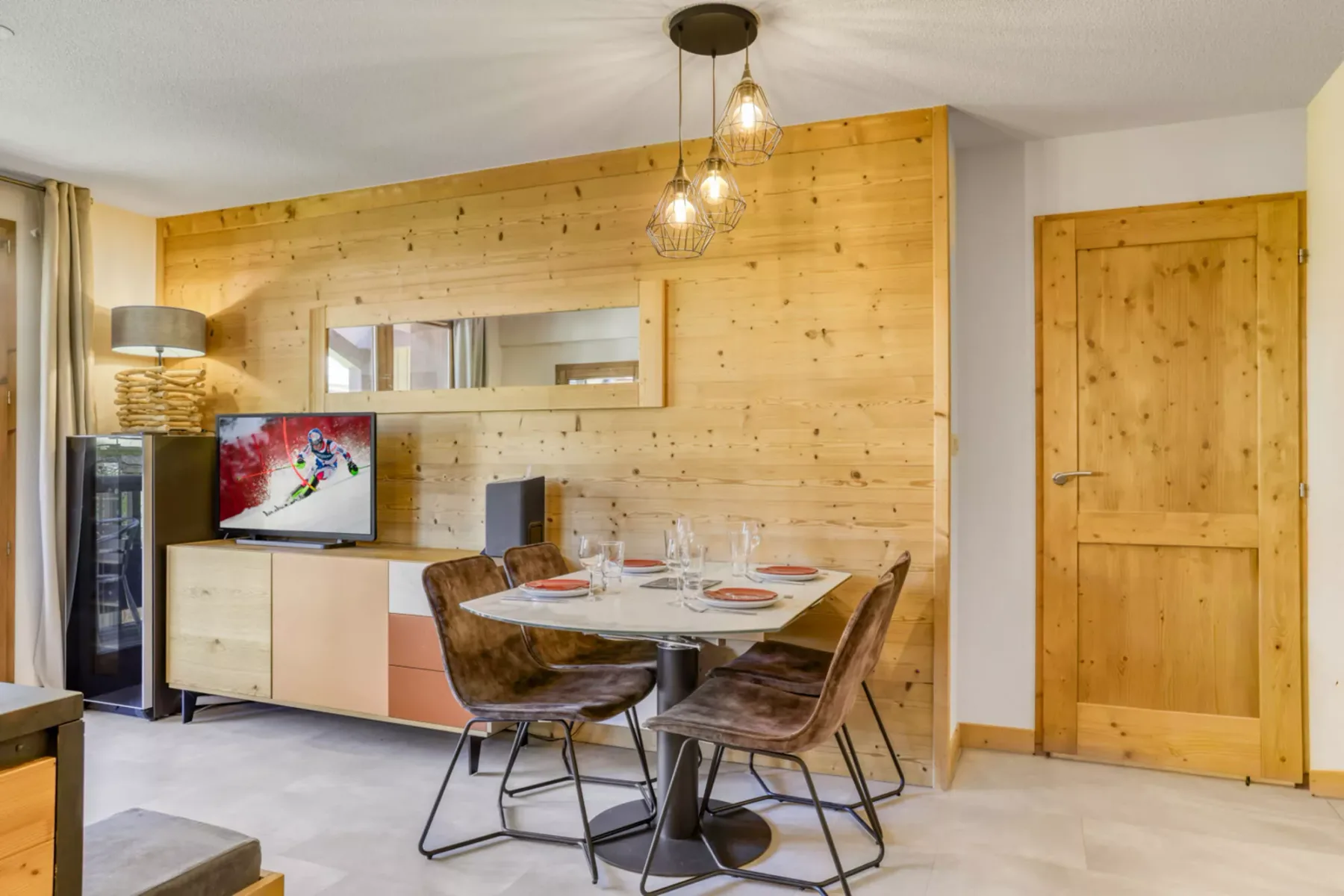 Comedor con una mesa y asientos junto a una pared revestida de madera.