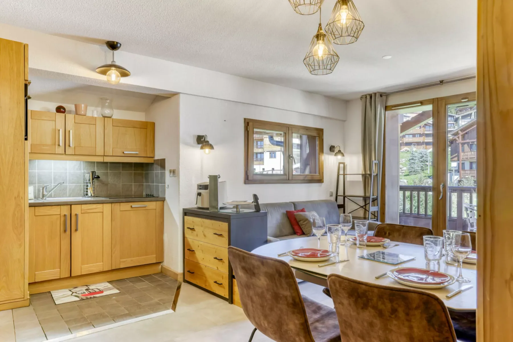 A dining area beside an open kitchen, with a table set near large windows.