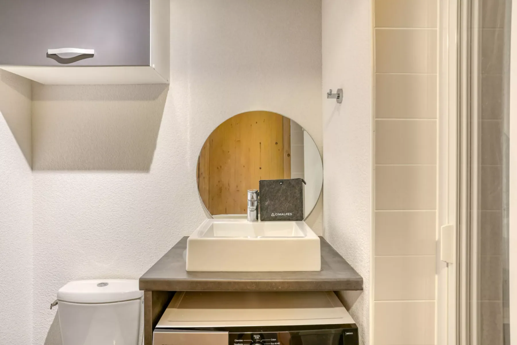 Un lavabo de baño con un espejo redondo y un lavamanos.