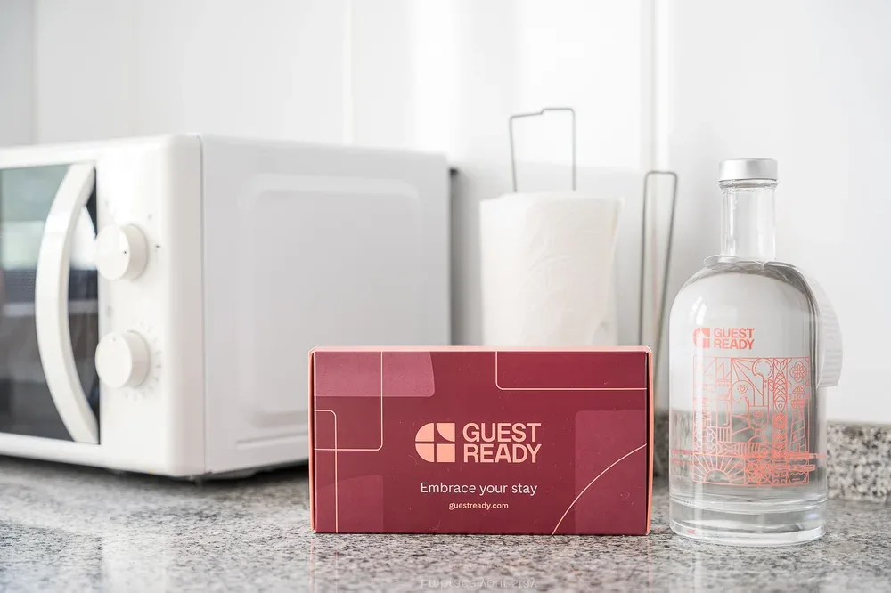 A kitchen counter displays a microwave, a red card, and a glass bottle.