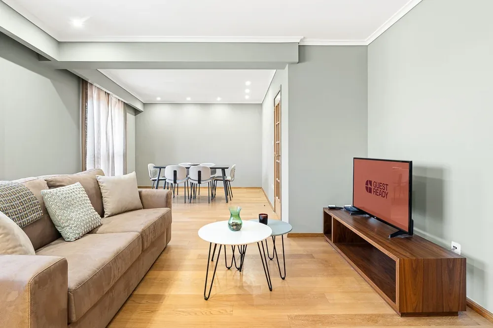 A living room with seating and a dining table in the background.