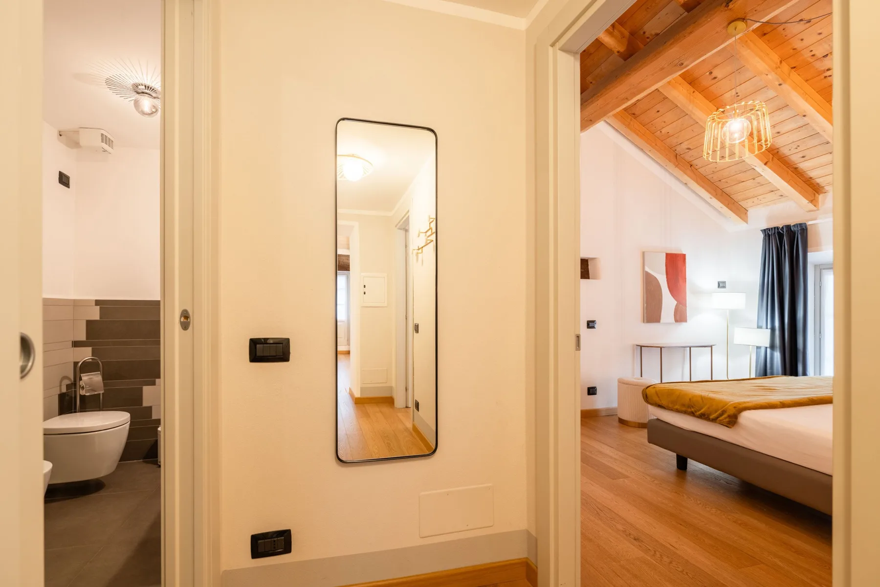 Un dormitorio con techo de madera y un baño contiguo.
