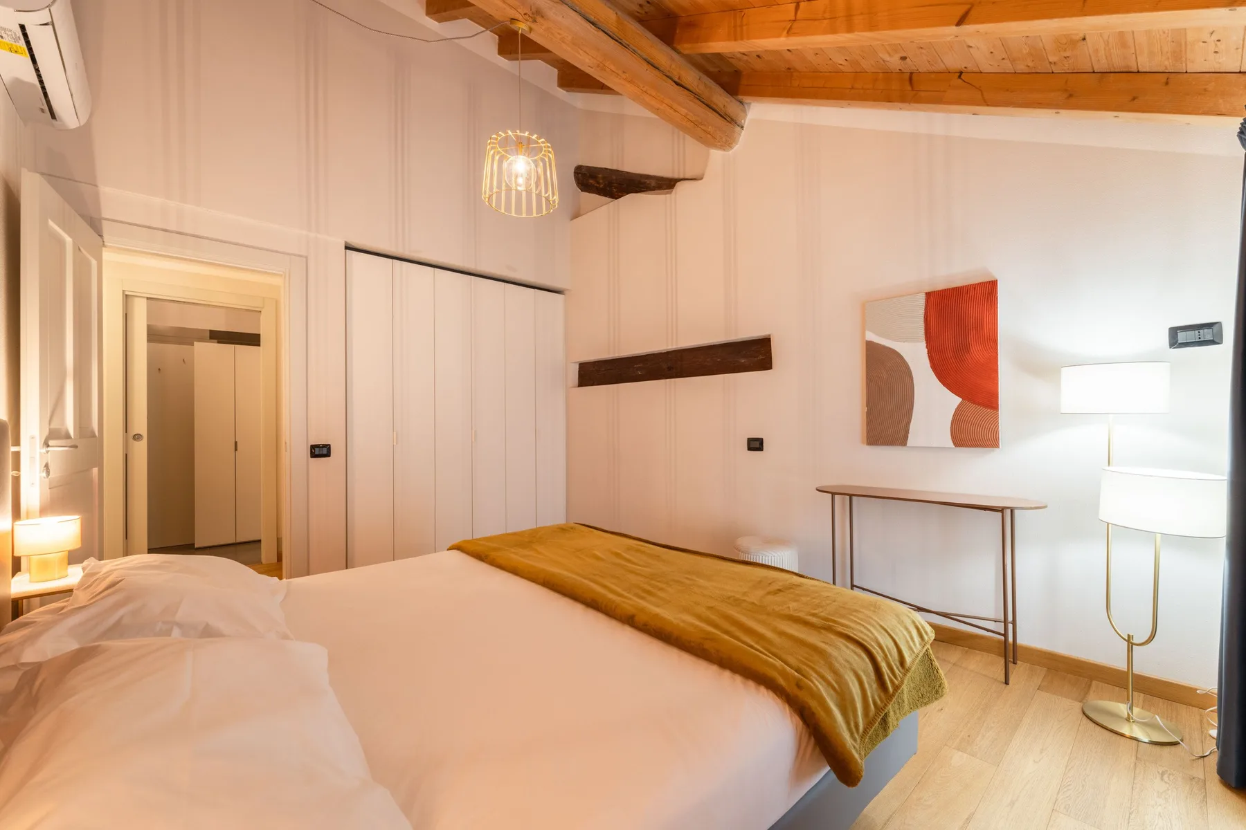 Un dormitorio con una cama, una mesa pequeña y una lámpara de pie.