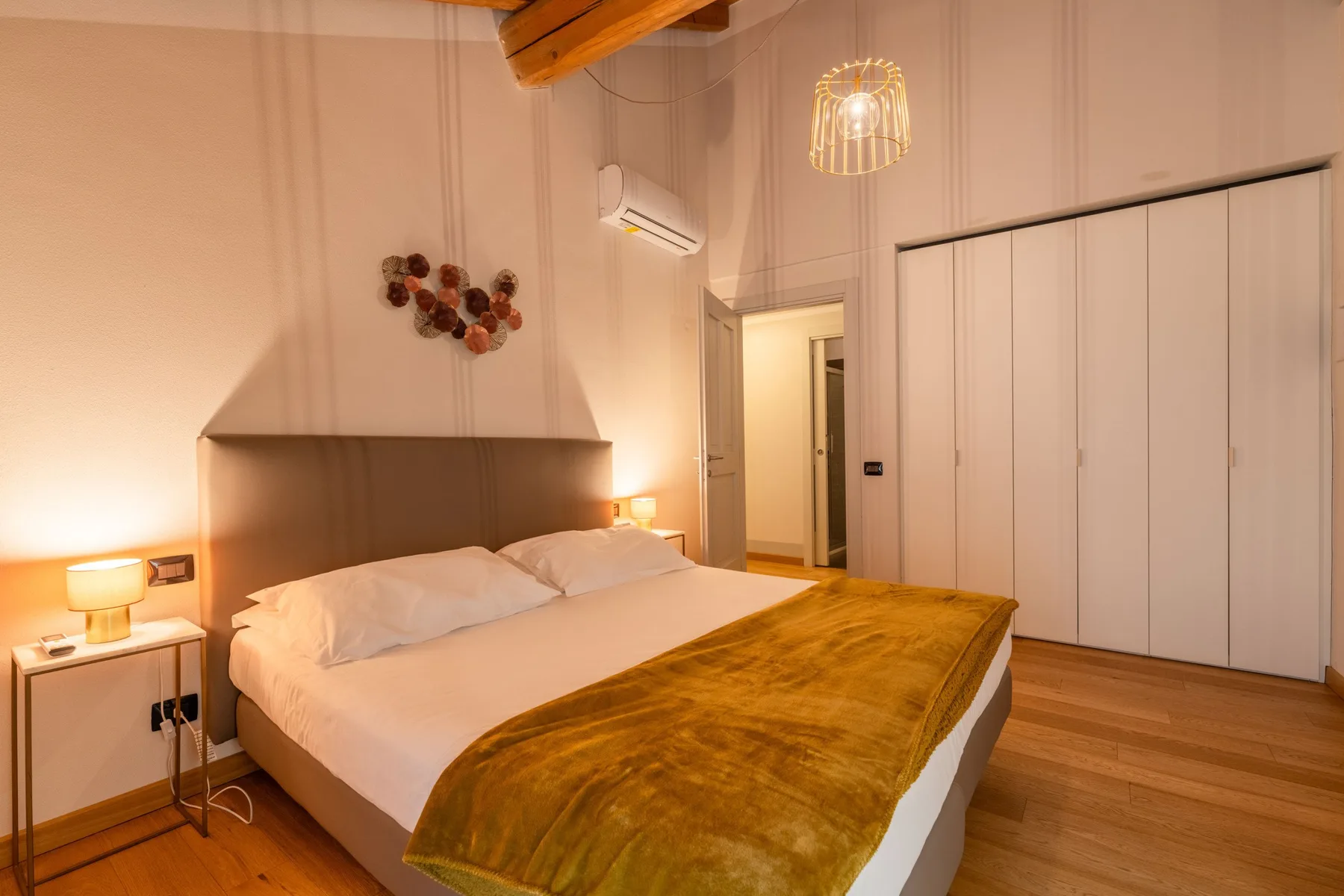 Un dormitorio con una cama grande, una manta marrón y armarios.