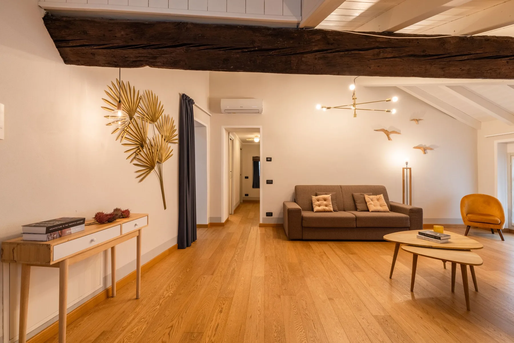 Una sala luminosa con un sofá y mesas de centro de madera.