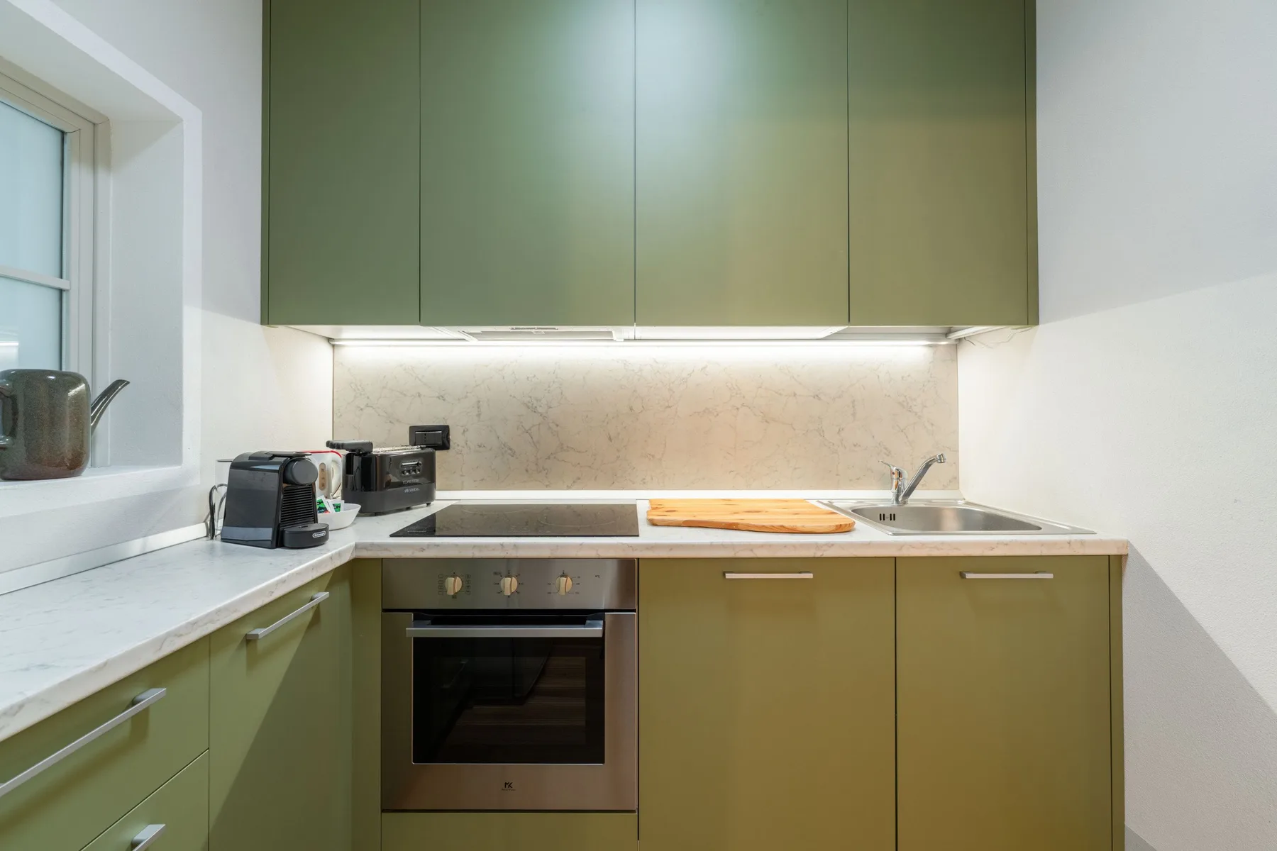 Una cocina moderna con gabinetes verdes, una encimera y un horno.