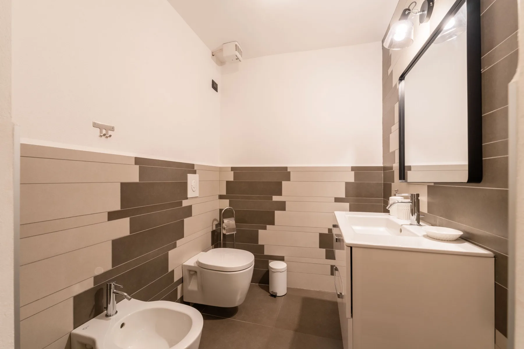 Un baño con inodoro, lavabo y espejo en la pared.