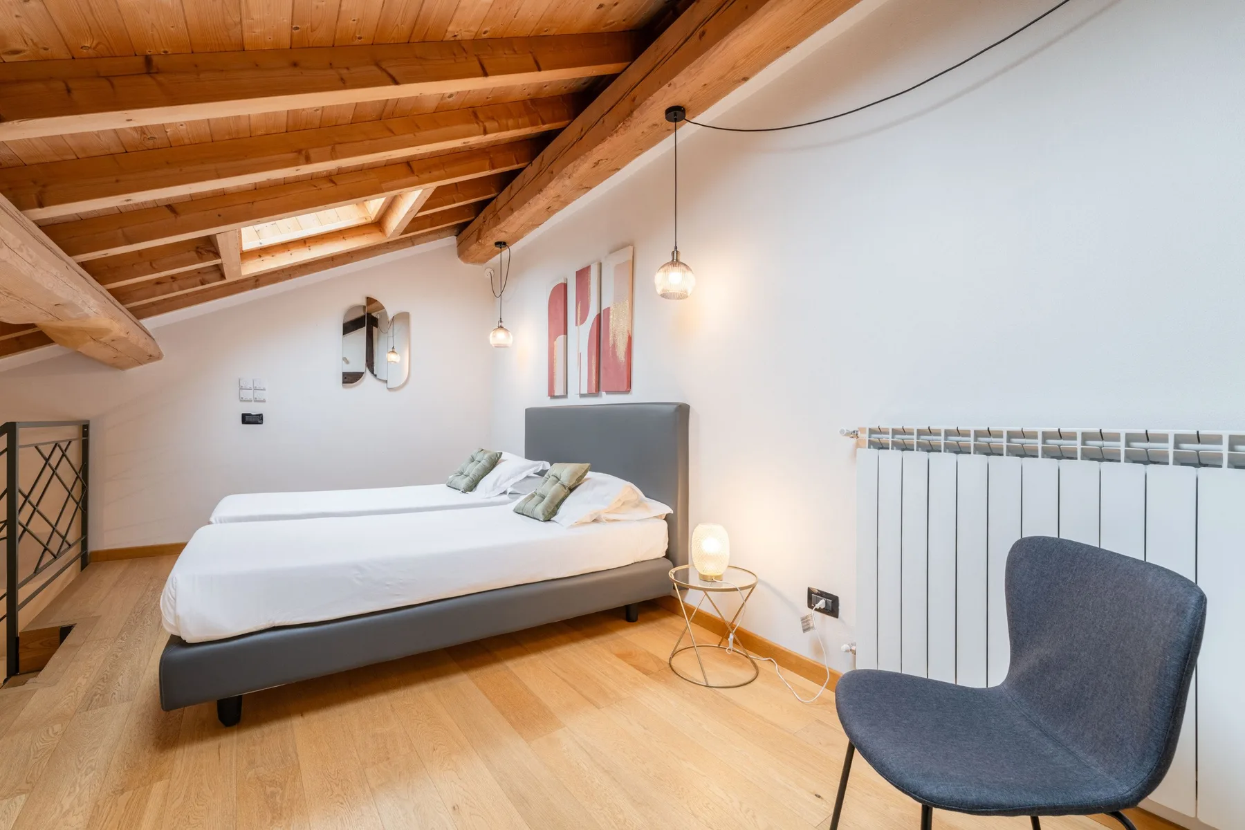 Un dormitorio luminoso con una cama bien tendida bajo un techo inclinado de madera.