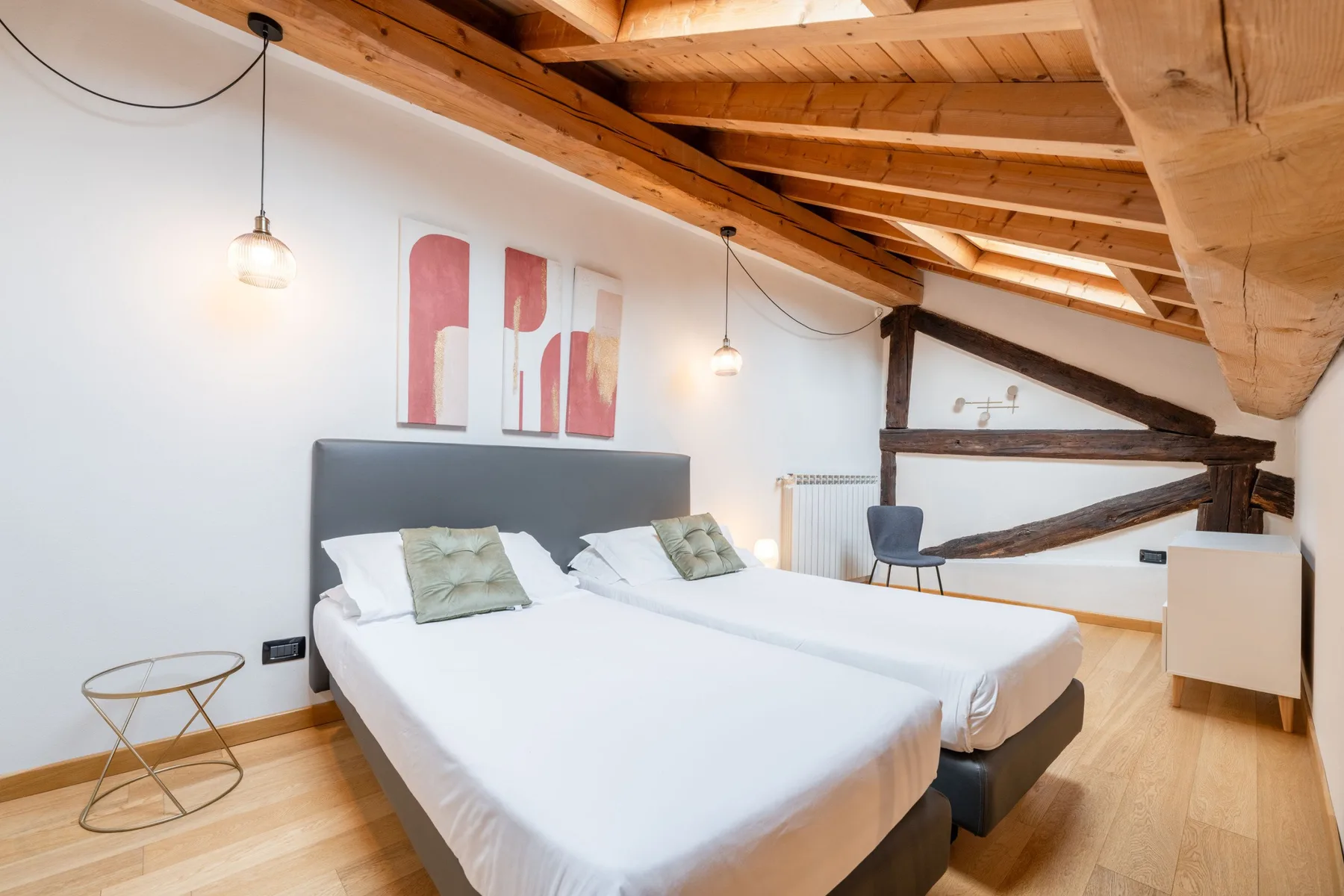 Un dormitorio con dos camas bajo vigas de madera expuestas.