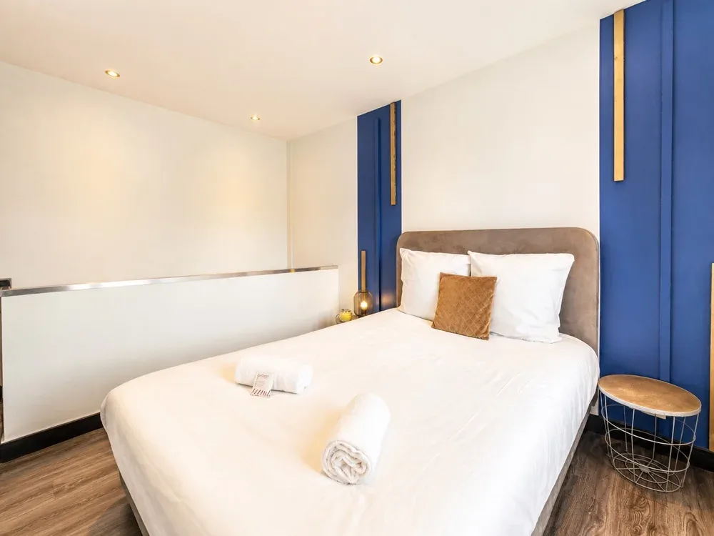 A bedroom with a neatly made bed and blue accent panels.