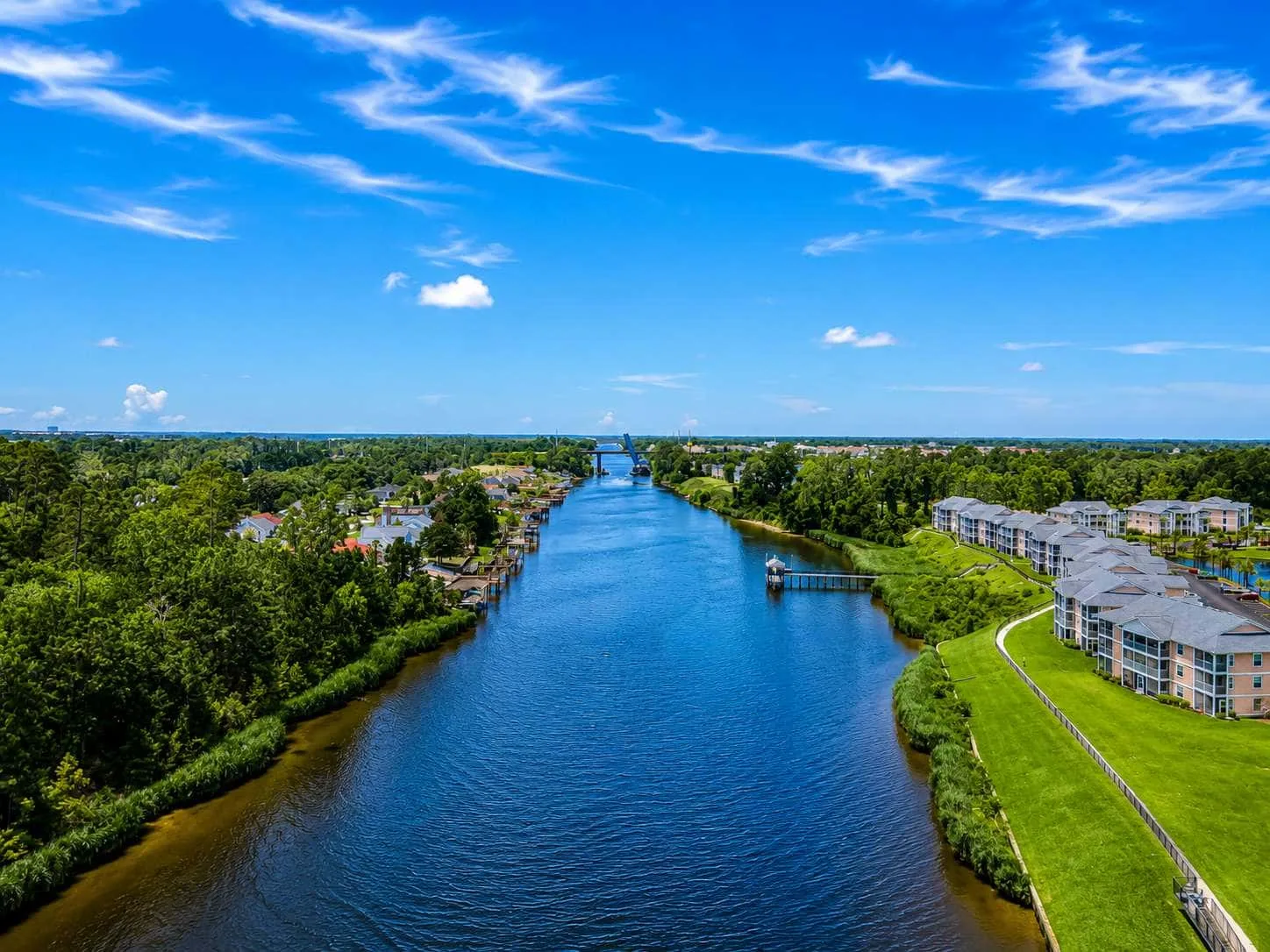 Aerial view of a canal bordered by green banks and buildings.