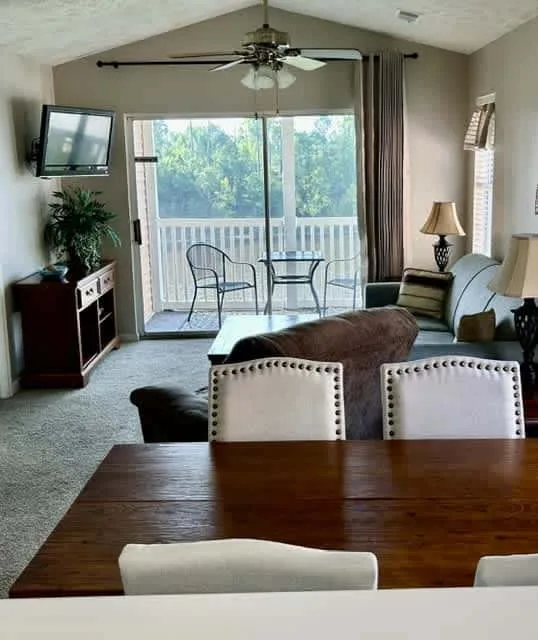 A living and dining area opens onto a balcony through large glass doors.