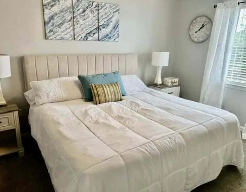 A bedroom with a large bed, bedside tables, and a curtained window.