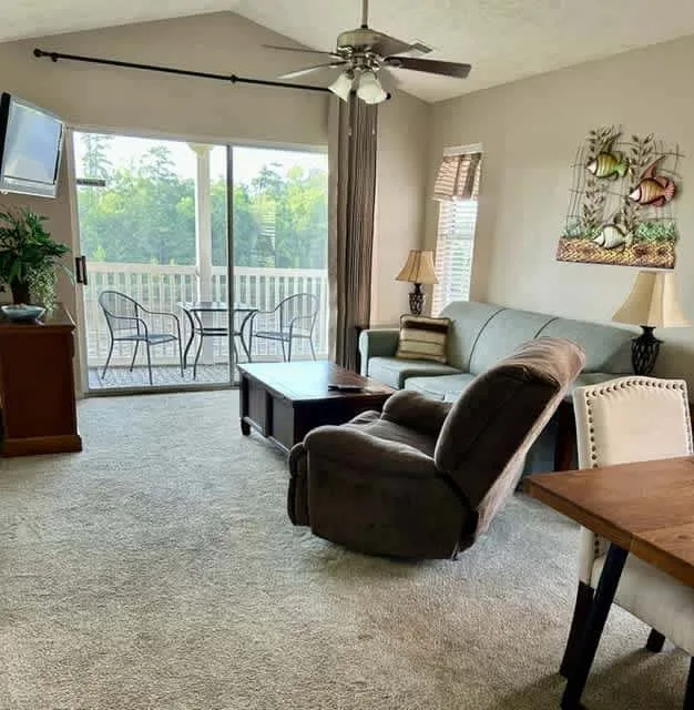 A living room with seating, a coffee table, and sliding glass doors opening to a balcony.