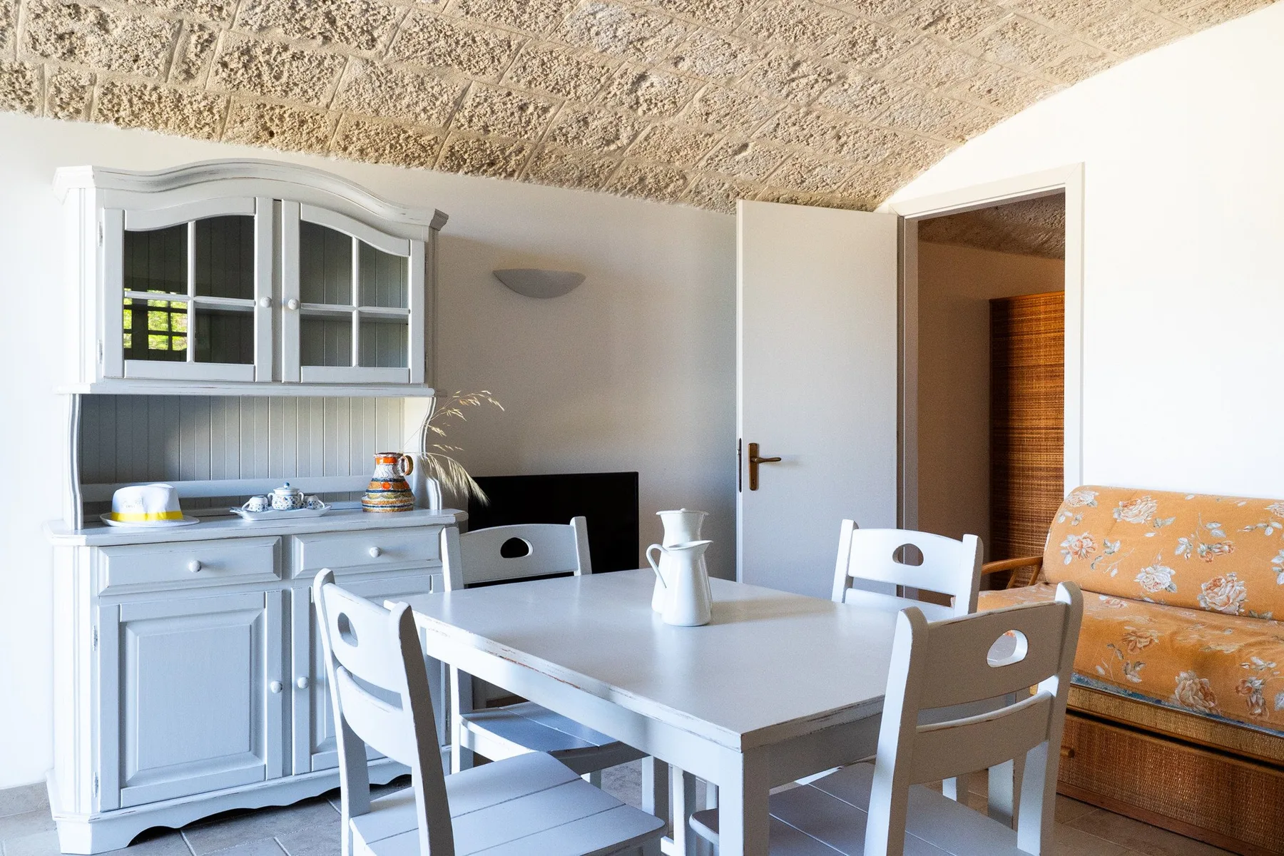 A dining area with a white table, chairs, and a built-in cabinet.