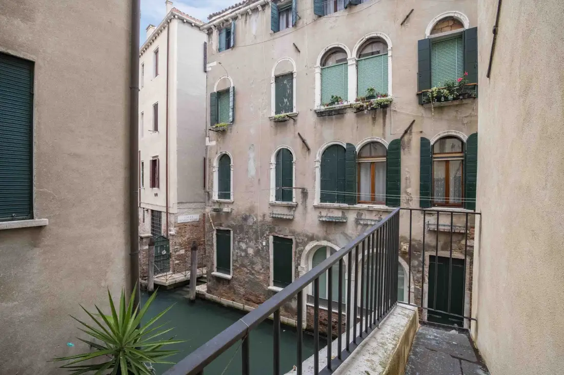 Un edificio junto al canal con ventanas arqueadas y un pasaje estrecho.