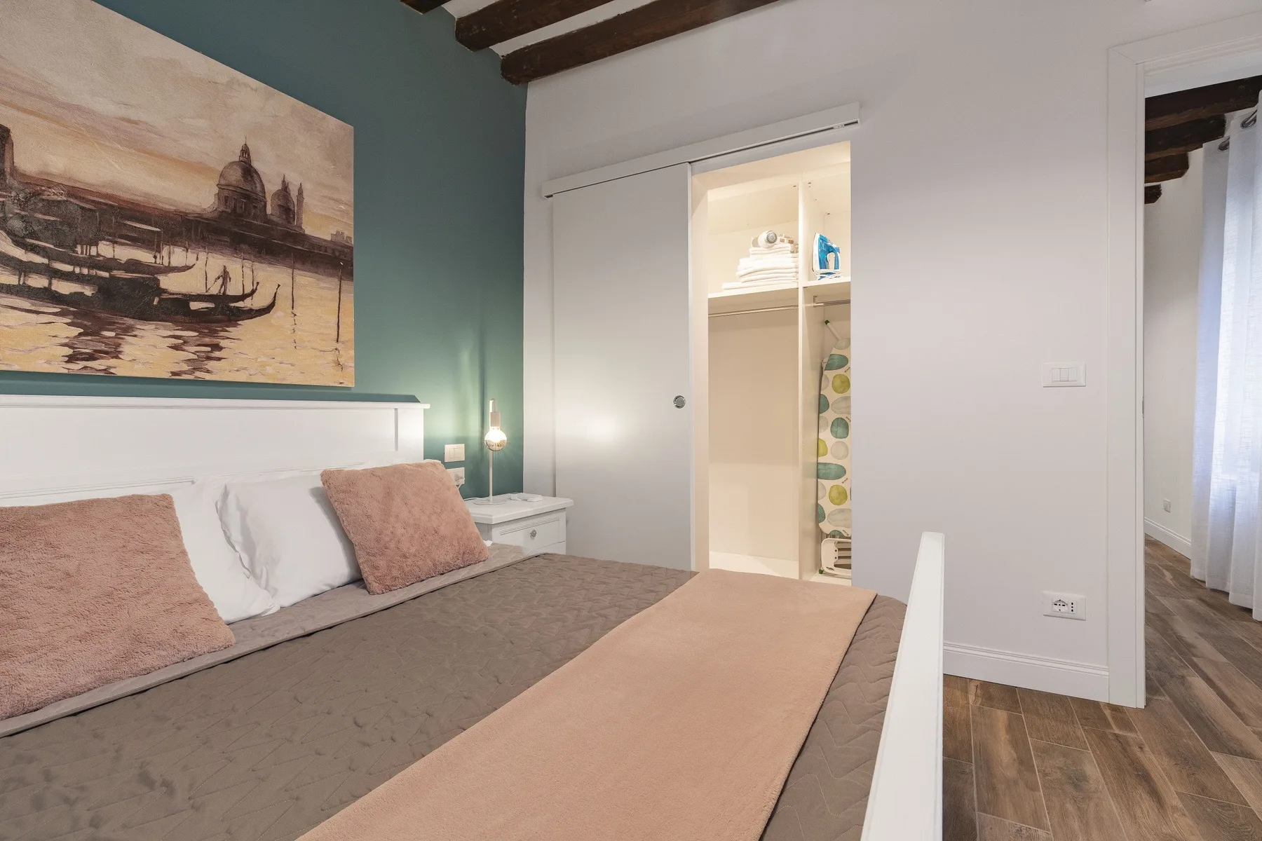 Un dormitorio con una cama, mesitas de noche y un armario abierto.