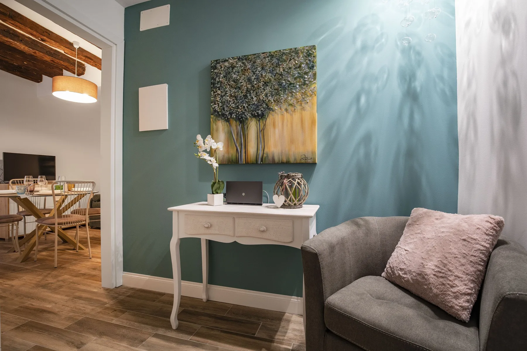 Una zona de estar con un sillón gris junto a una pequeña mesa consola.