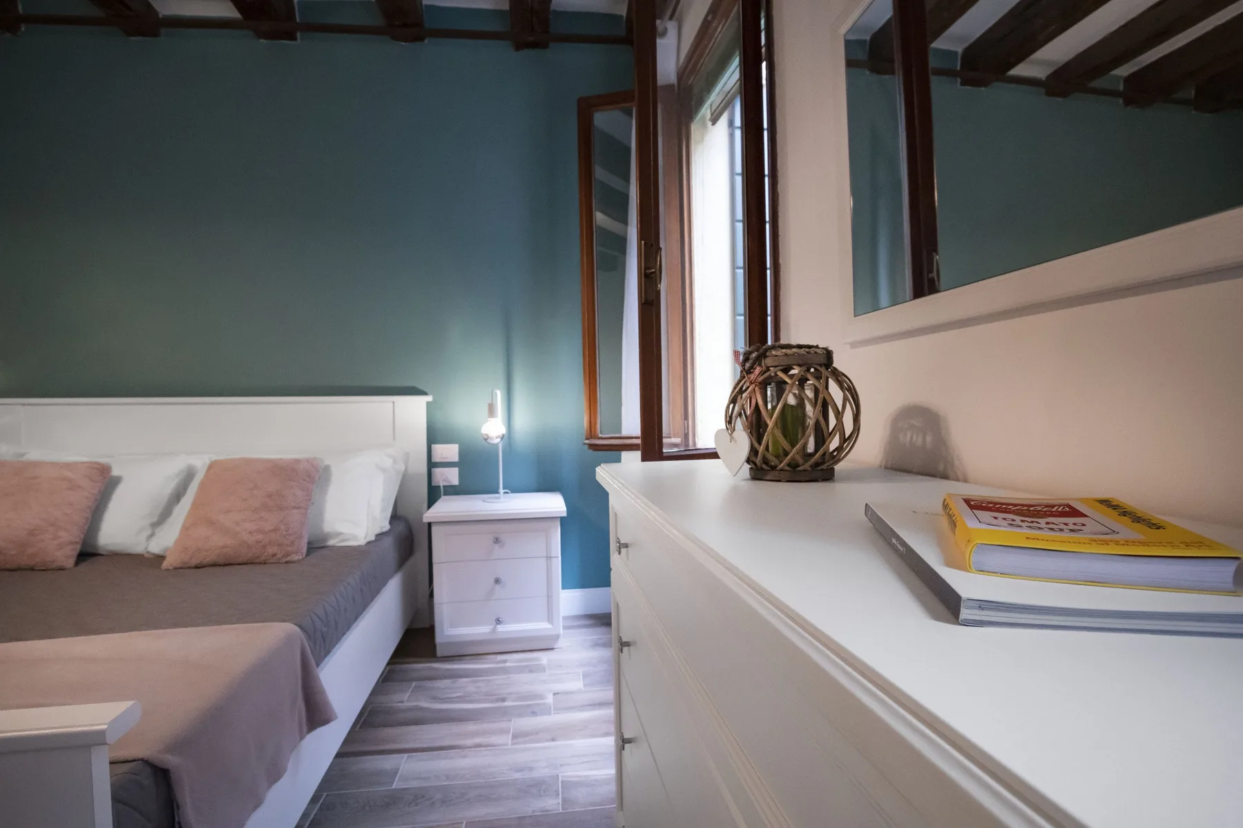 Un dormitorio con una cama, una mesita de noche y una cómoda blanca.