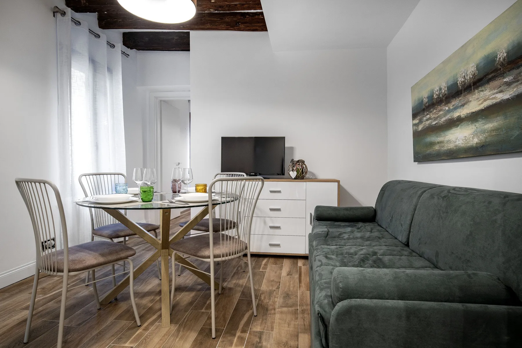 Una sala de estar y comedor con una mesa, asientos y un televisor.