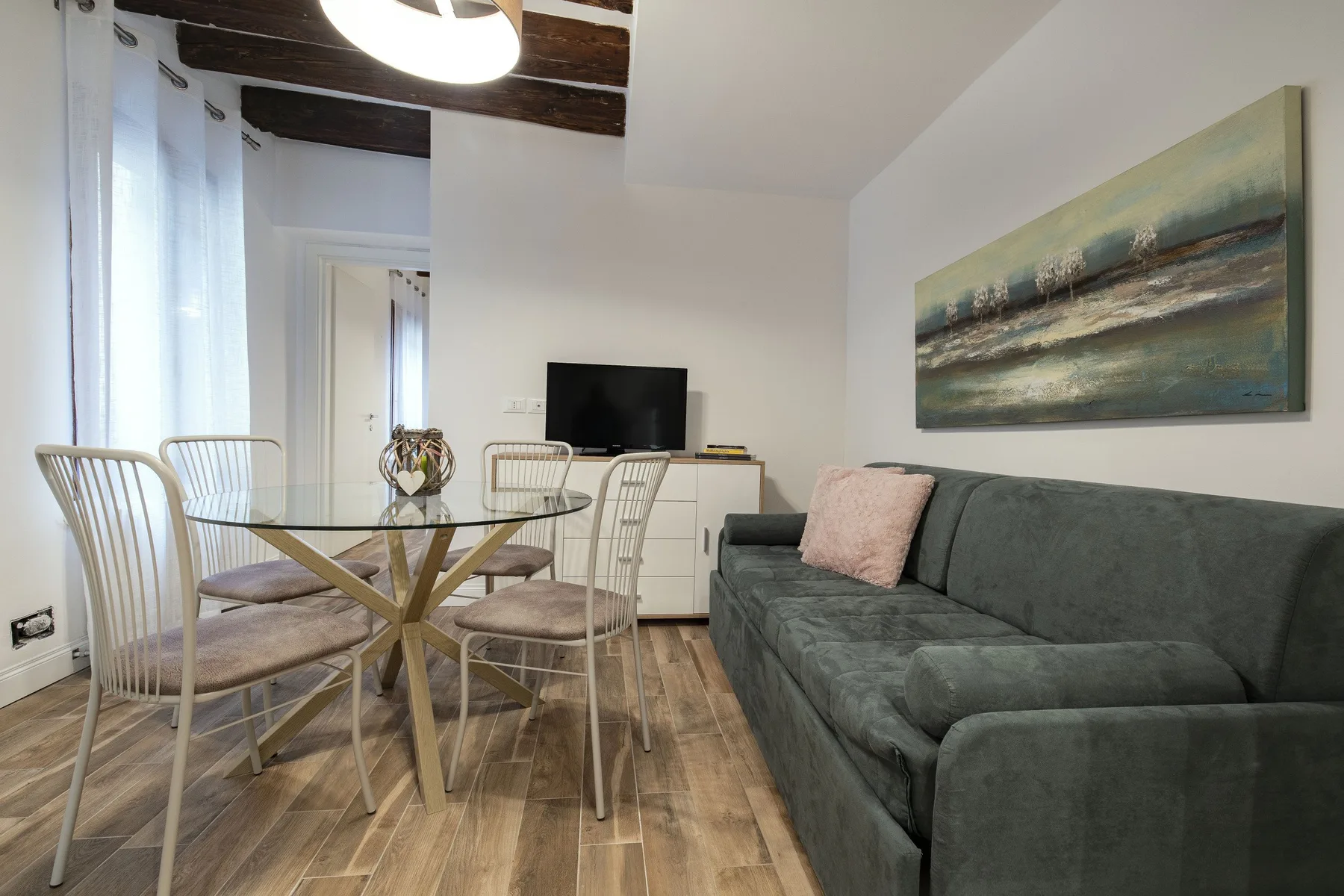 Una sala de estar y comedor con sofá, mesa de comedor y televisor.