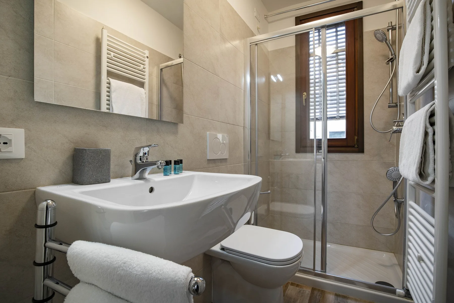 Un baño alicatado con lavabo, inodoro y ducha con mampara de vidrio.