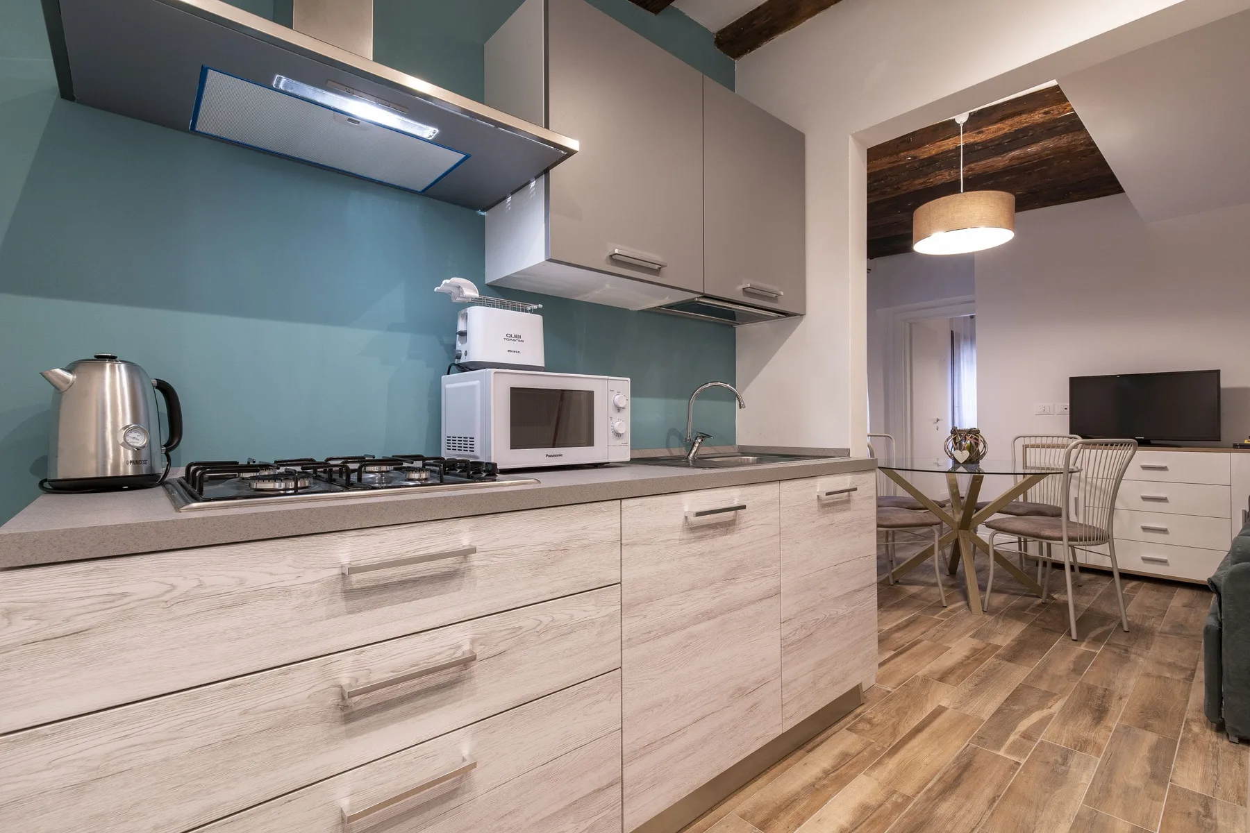 Una cocina moderna con placa de cocción, microondas y encimera se abre a una sala de estar.