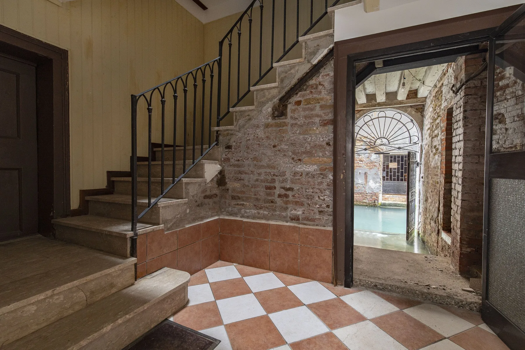 Una escalera interior con suelo de baldosas y un arco.