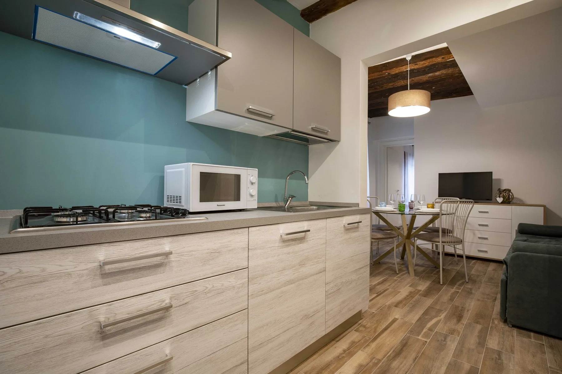 Una cocina con encimera, cocina y microondas se abre a un comedor.