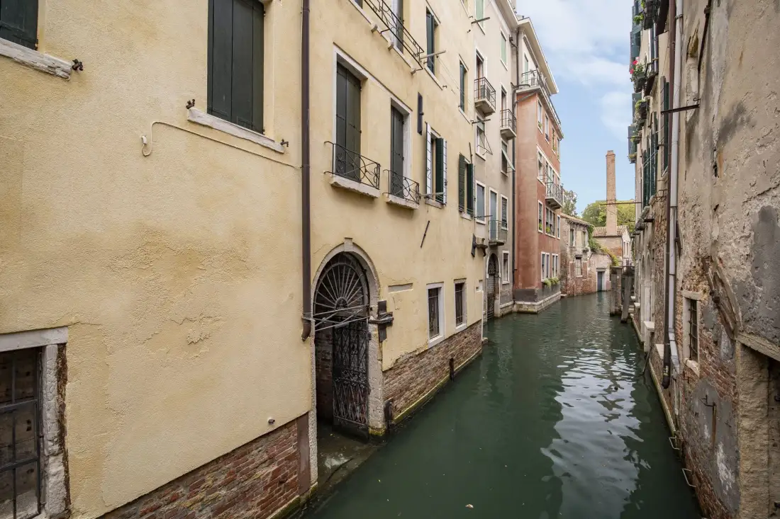 Un canal estrecho pasa entre edificios muy juntos en una zona urbana antigua.