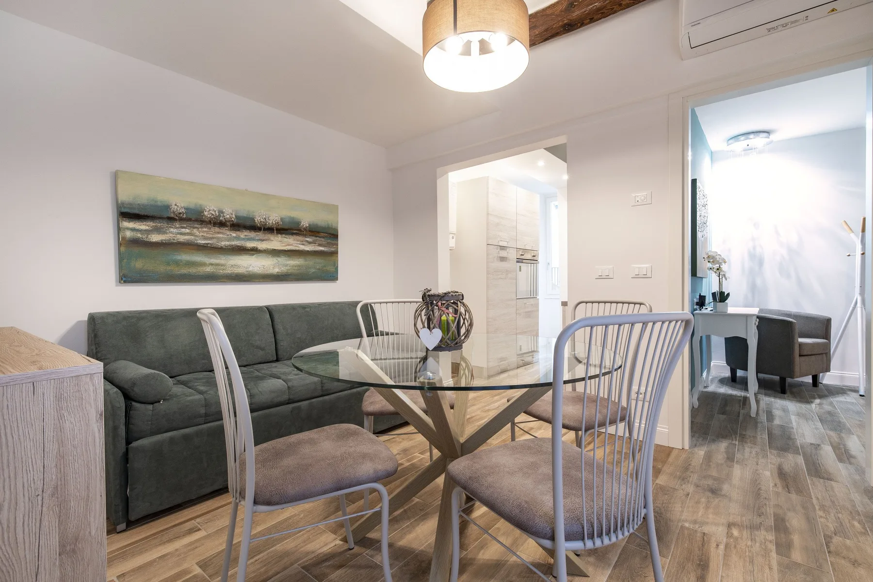Comedor con una mesa de cristal y asientos junto a una sala de estar.