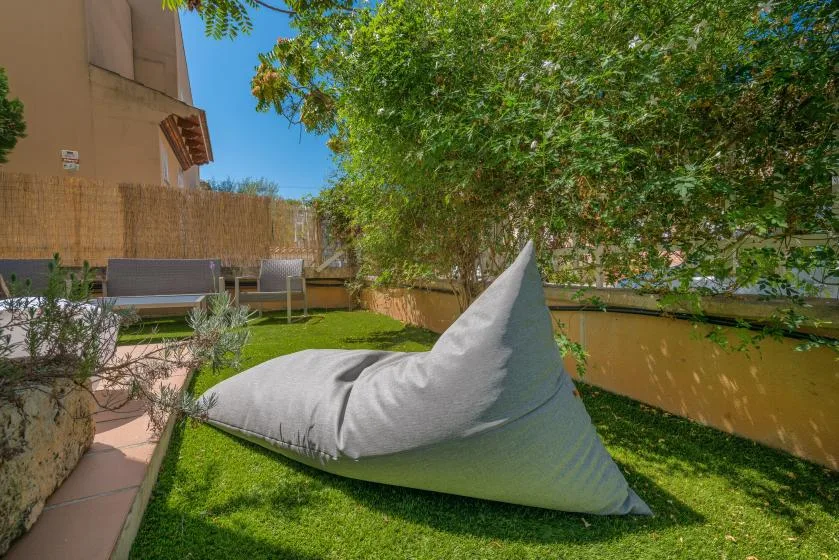 Una zona de jardín tiene un gran puf gris sobre el césped.