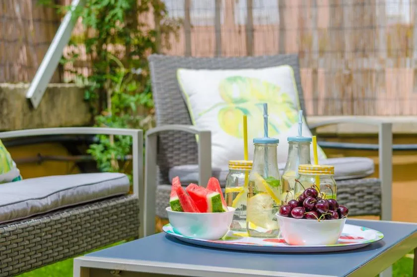 Una zona de estar al aire libre con bebidas y cuencos de fruta sobre una mesa.