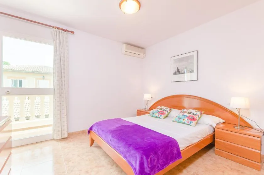 Un dormitorio con una cama de madera, almohadas coloridas y una manta morada.