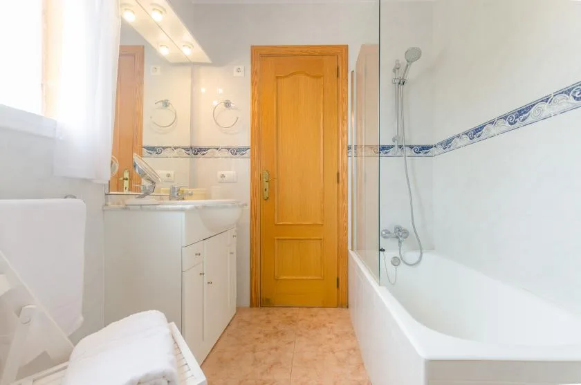 Un baño con bañera, lavabo y puerta de madera.
