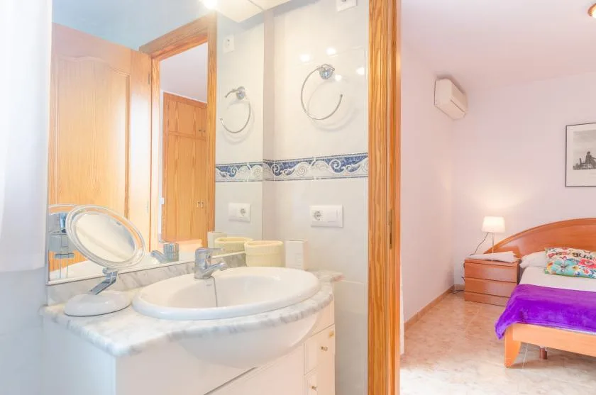 Un lavabo de baño da paso a un dormitorio con una cama.