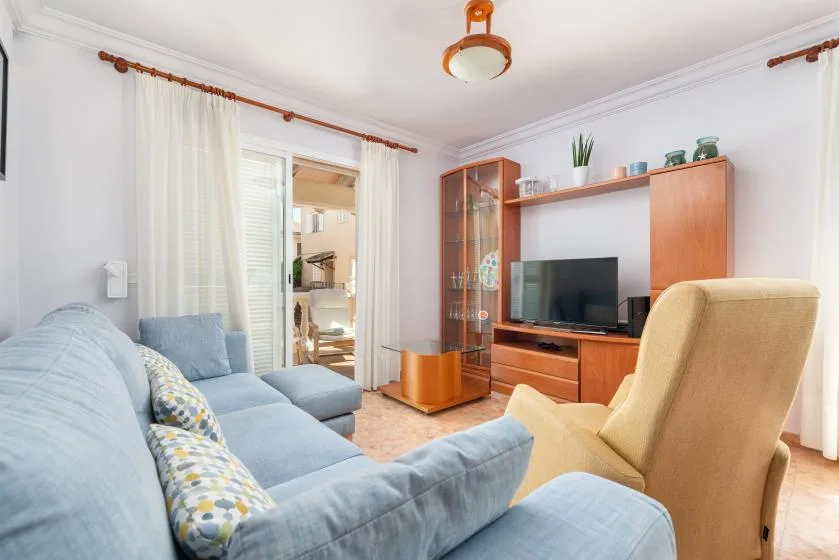 Una sala de estar con asientos azul claro, un televisor y muebles de madera.