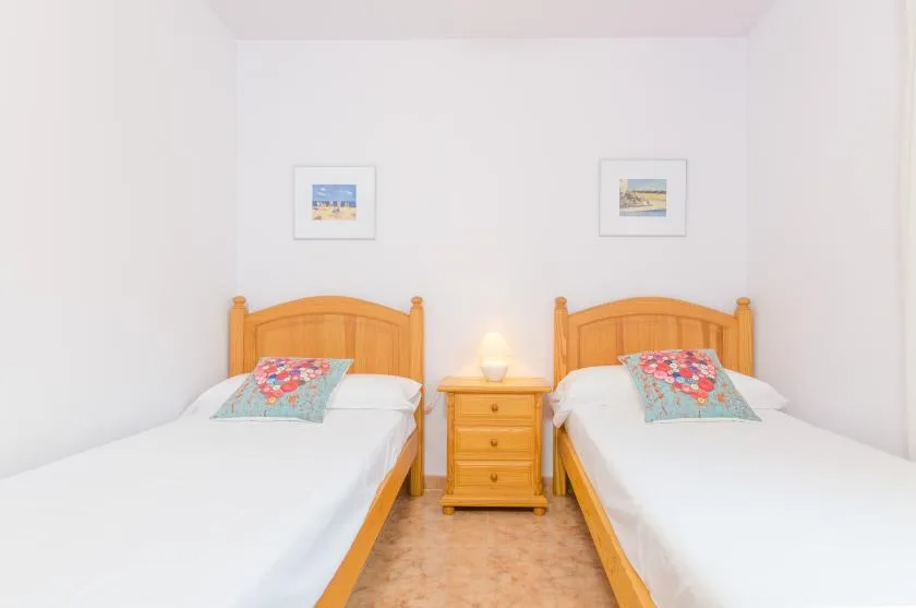 Un dormitorio con dos camas y una mesita de noche entre ellas.