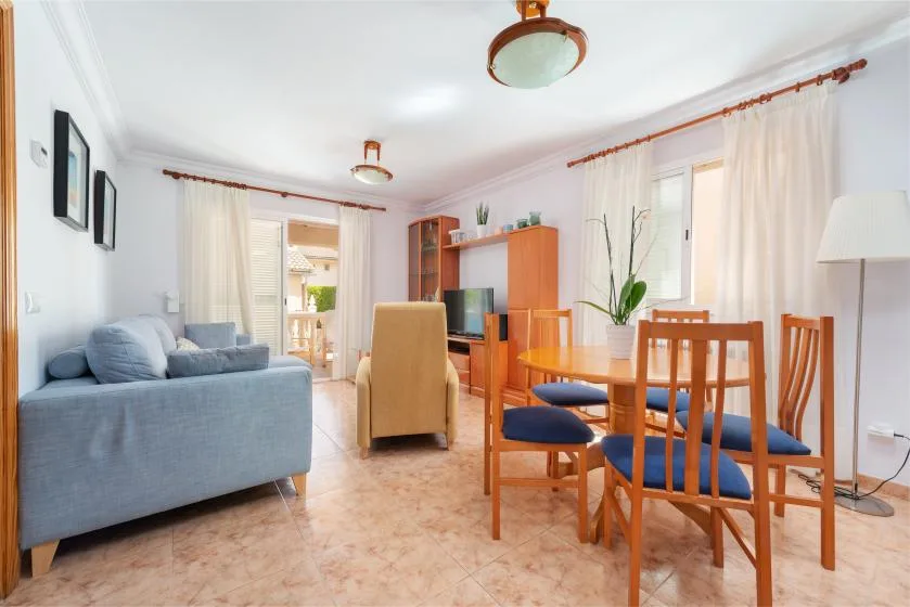 Una luminosa sala de estar y comedor con asientos, una mesa y grandes ventanas.