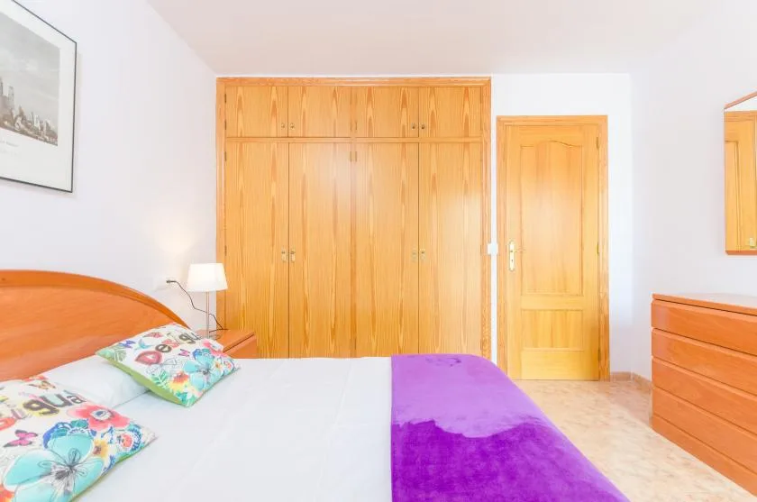 Un dormitorio con una cama, armarios de madera y una puerta a juego.