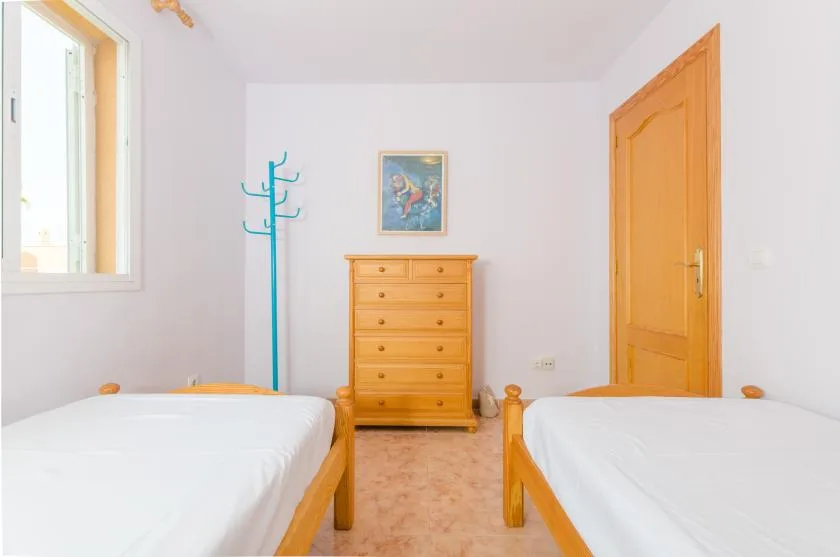Un dormitorio con dos camas, una cómoda de madera y una ventana.