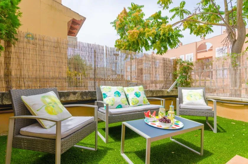 Una zona de estar al aire libre con asientos acolchados alrededor de una mesa baja.