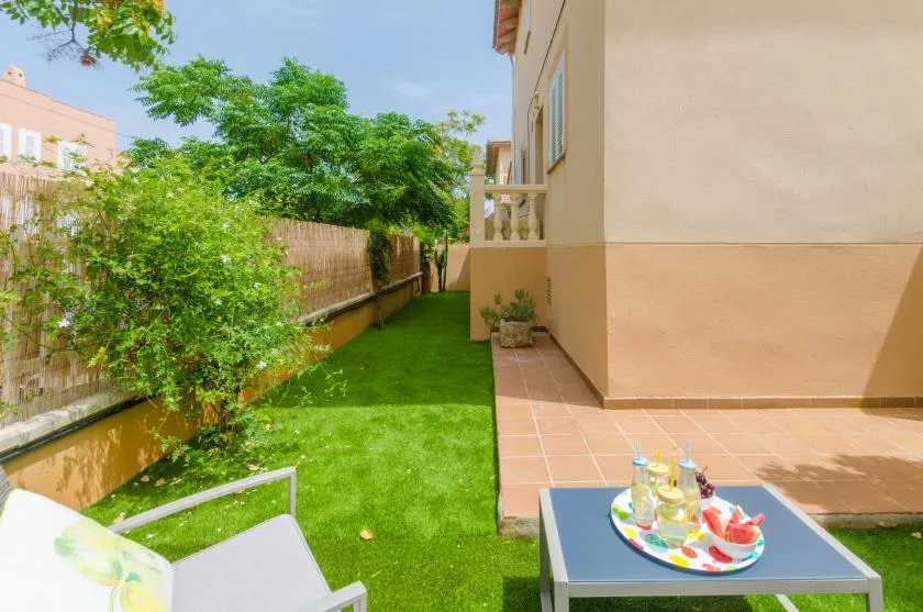 A sunny outdoor patio beside a green lawn, with a table and seating.