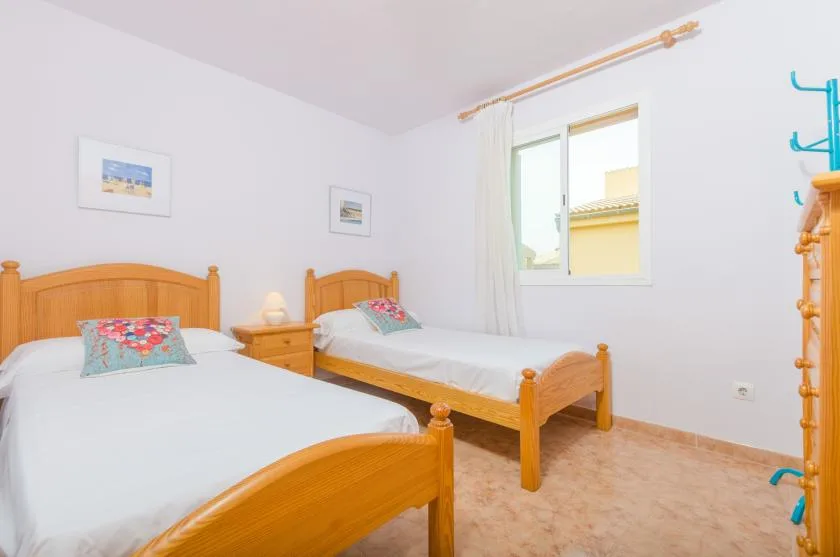 Un dormitorio luminoso con camas de madera y una ventana.