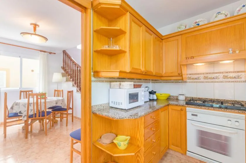 Una cocina luminosa con armarios de madera y un comedor al fondo.